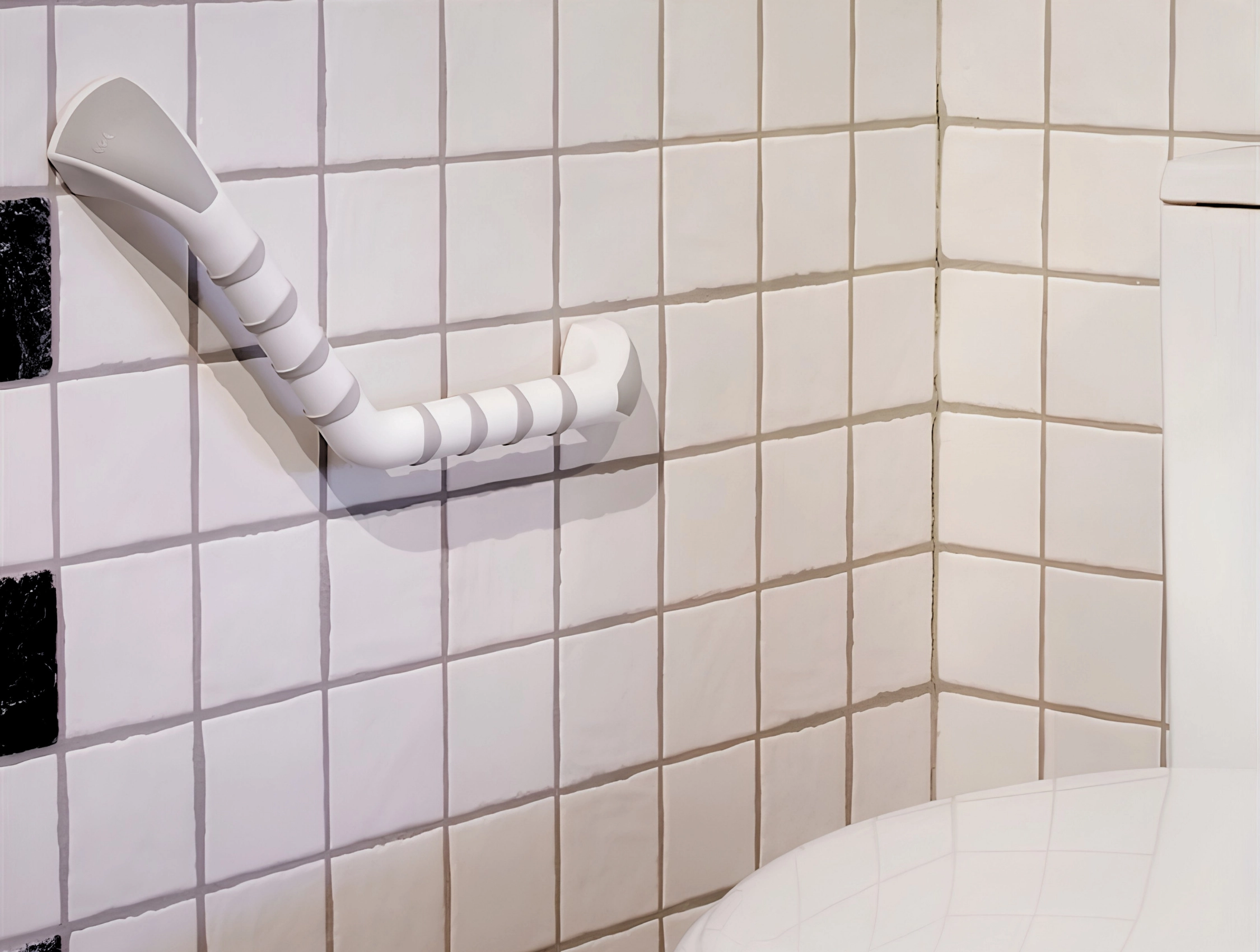Vitt Etac Handy stödhandtag monterat på kaklad badrumsvägg